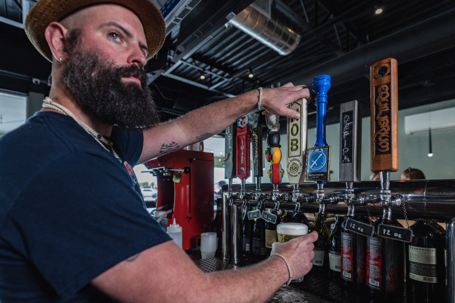 A bartender pours a draft beer from the taps at Madison Avenue Pizza