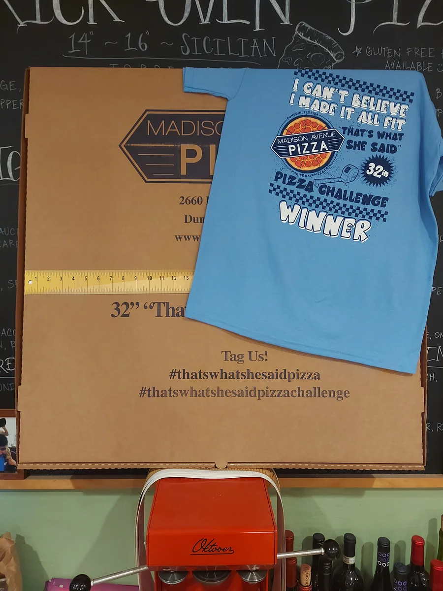 A 32-inch Madison Avenue Pizza box with a measuring tape and pizza challenge winner shirt