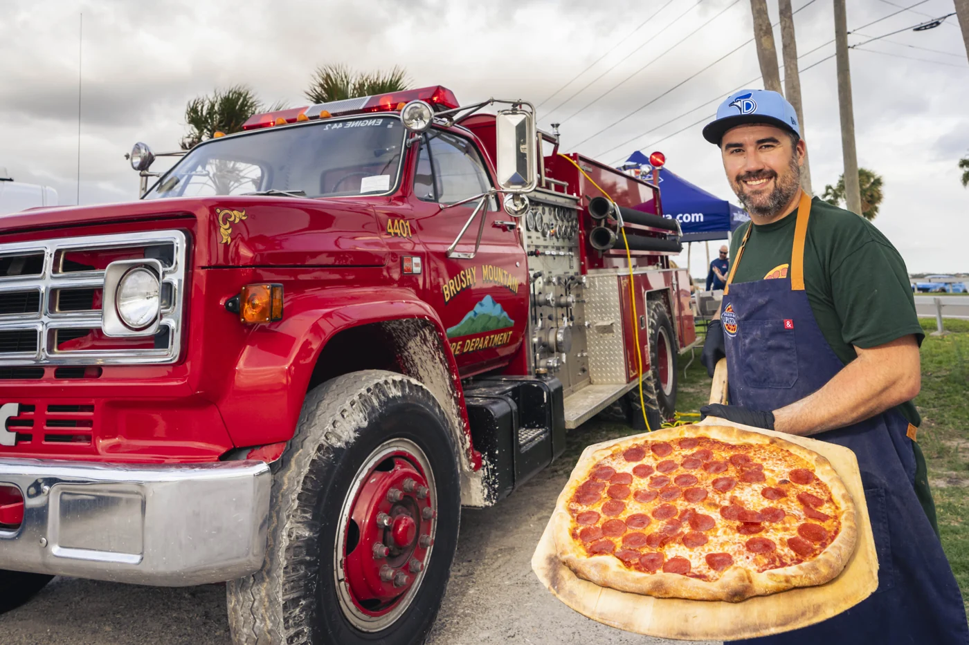 Sean Ferraro holding a pizza beside Madison’s fire truck catering kitchen